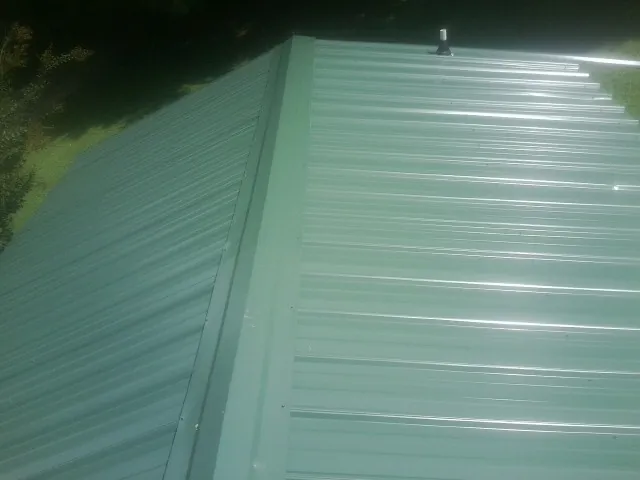 New green metal panels meeting at the ridge of a roof — Flat Roof Repair work by our crew in Owensville