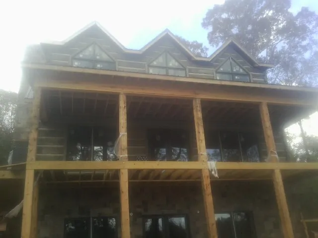 Dormers and porch framing on a large log home under construction — Roof Coating work by our crew in Owensville