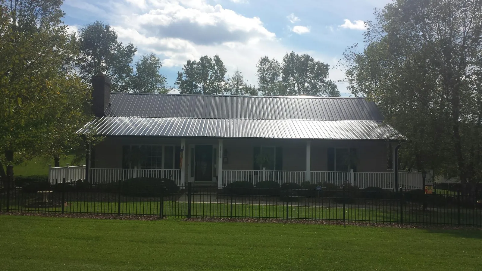 Gray metal roof on a brick ranch with a full width front porch — Gutter Guard Installation work by our crew in Owensville